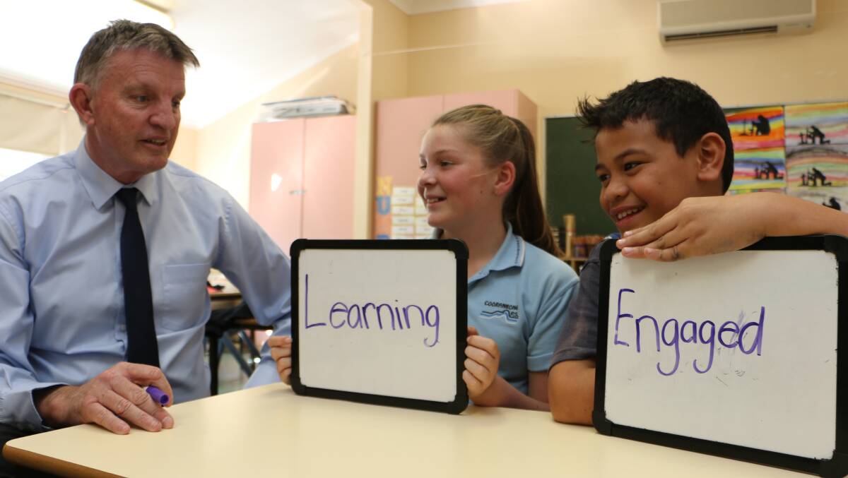 WORD PLAY: John Fleming with Cooranbong students Millie Duroux, 12, and Elvan Tanuvasa, 10. Picture: David Stewart