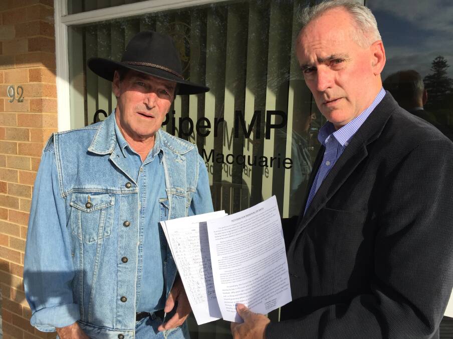 ENOUGH ALREADY: John Rose, left, presents Greg Piper with the petition calling for authorities to act on the flying fox problem at Blackalls Park. Picture: Supplied