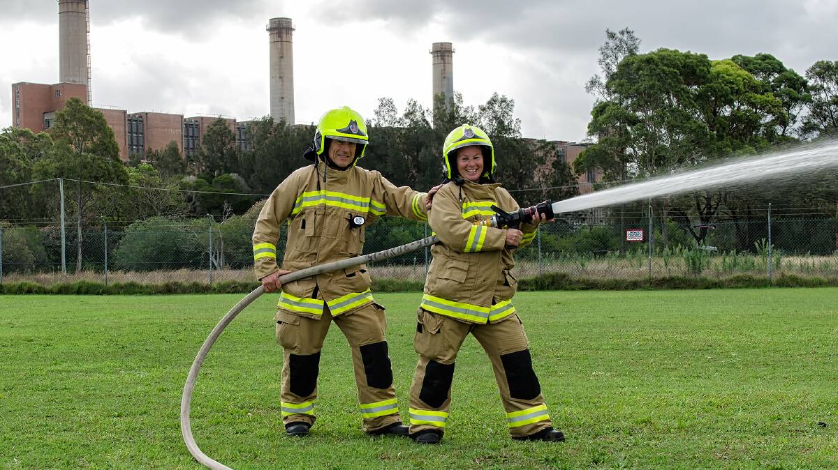 TRY IT: Firefighters Ross Murdoch and Deb Alfonsi during a hose drill at Wangi Wangi Oval. Picture: Chris VanderSchaaf