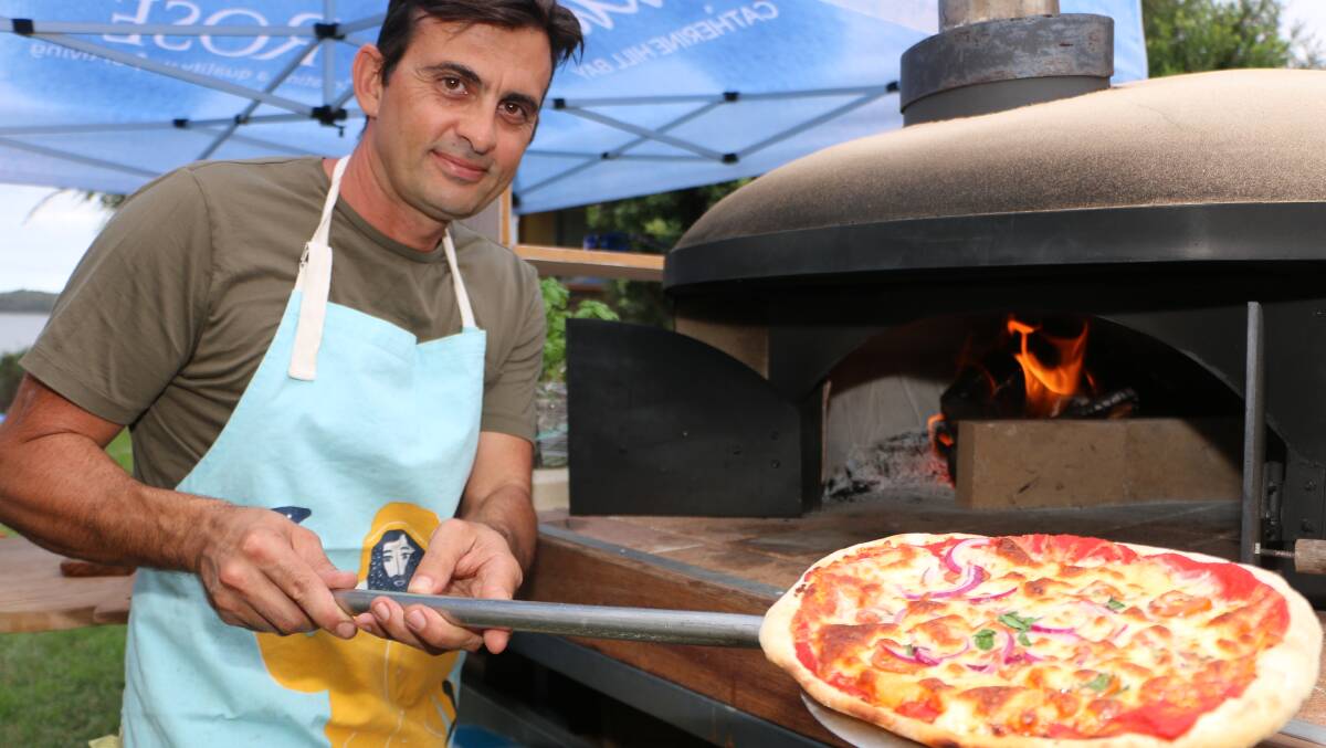 SMART DESIGN: George Kalaf pulls a freshly cooked pizza from his mobile wood-fired oven at South Lake Macquarie Amateur Sailing Club on Friday. Picture: David Stewart