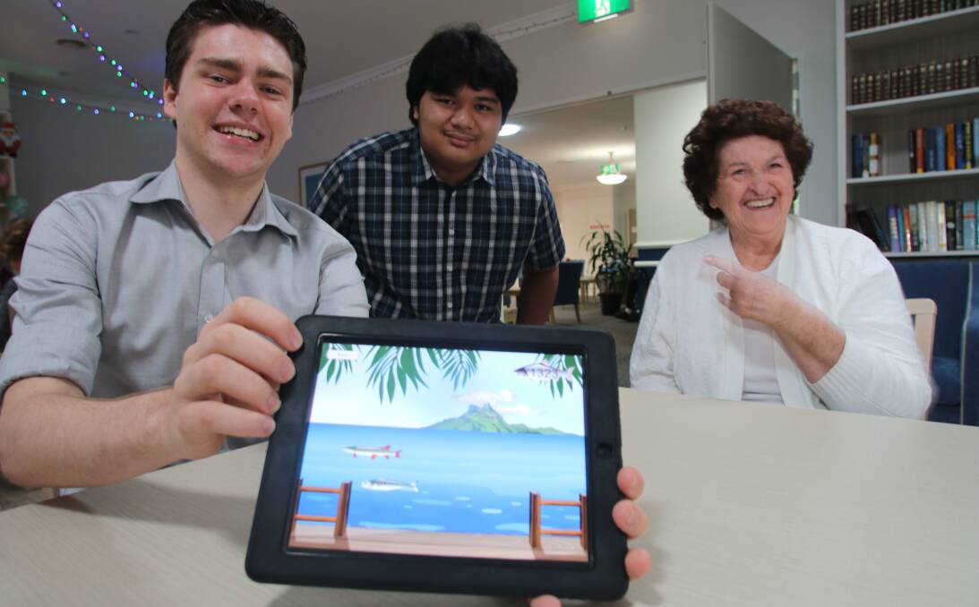 APPY DAYS: Avondale School students Andrew Thompson, left, and Joshua Masangcay with resident Barbara Croxin at Allity Aged Care’s Bayside facility. Picture: David Stewart