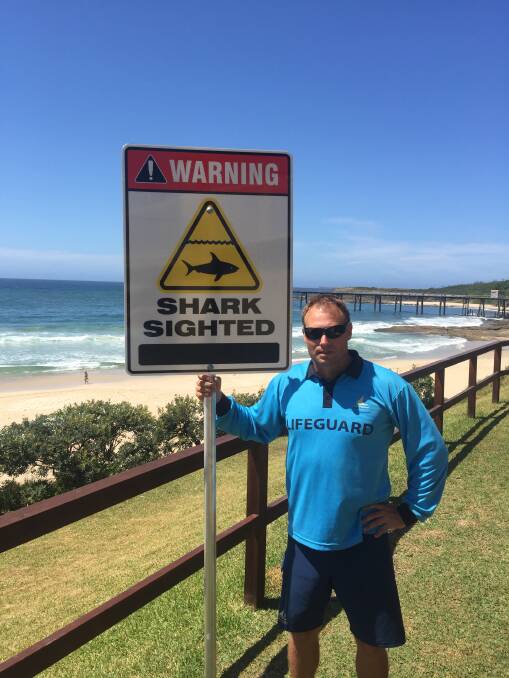 INFORMED: Lake Macquarie City Council beach lifeguard services team leader, Paul Stone, with the new shark sighting signage at Catherine Hill Bay Beach. Picture: Supplied
