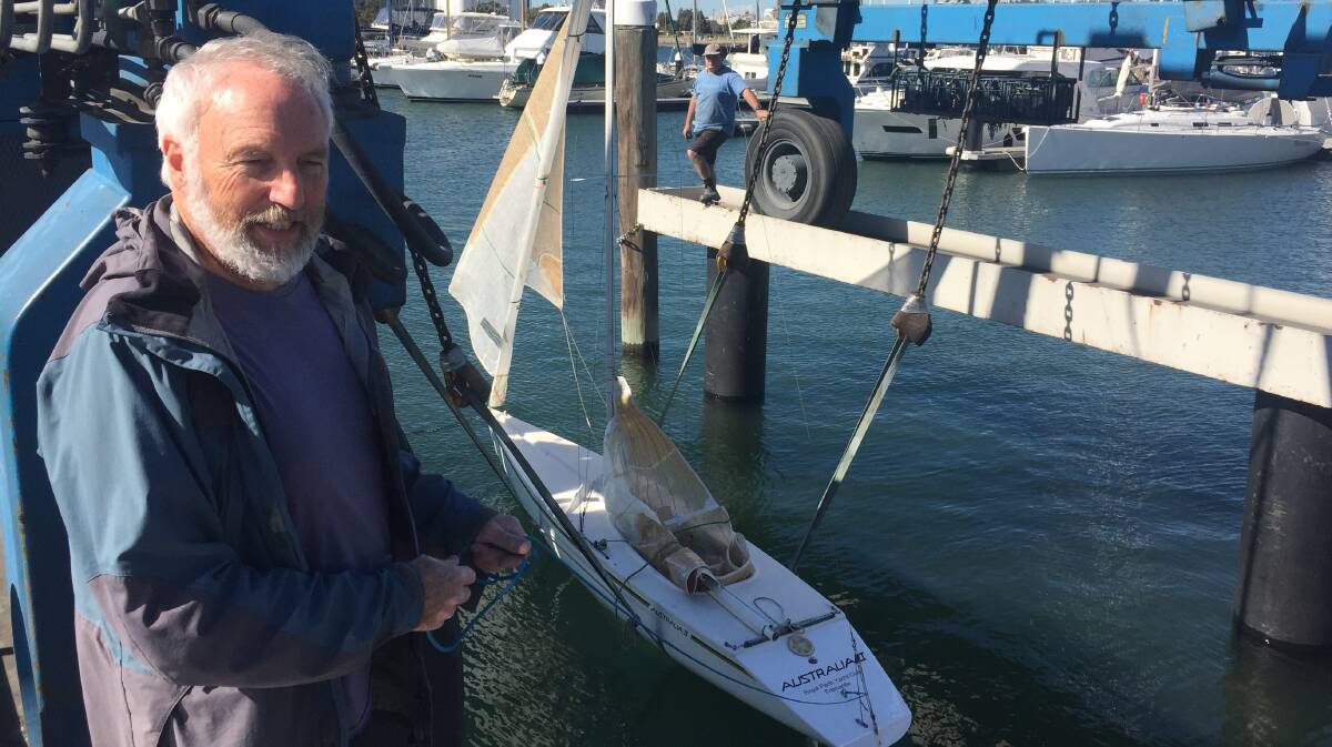Co-owner of the Australia II replica, John Beach, holds a line to the dinghy as it is prepared for sailing. Picture: Scott Bevan