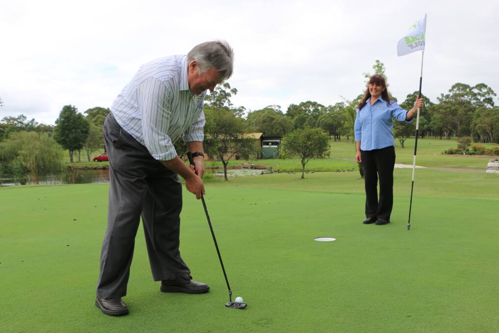 CAN'T MISS: Morisset Country Club chief executive Ian Taylor putts while staffer Robyn Shaw holds the flag.