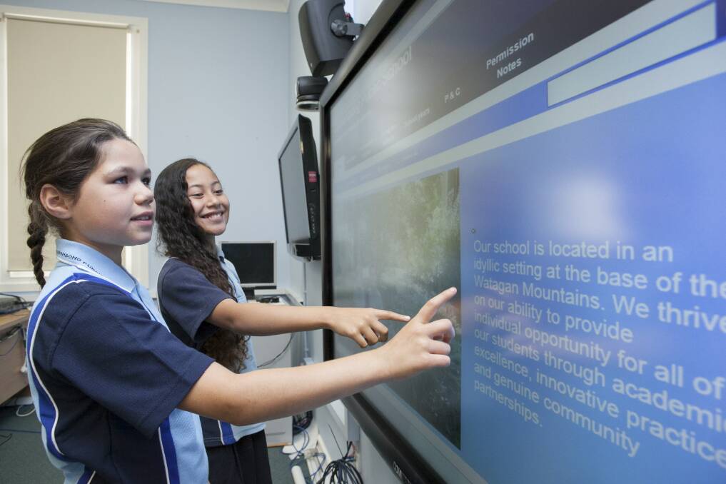SWITCHED ON: Students Evon Browne and Vanessa Gallagher with one of the school’s LED touch screens.