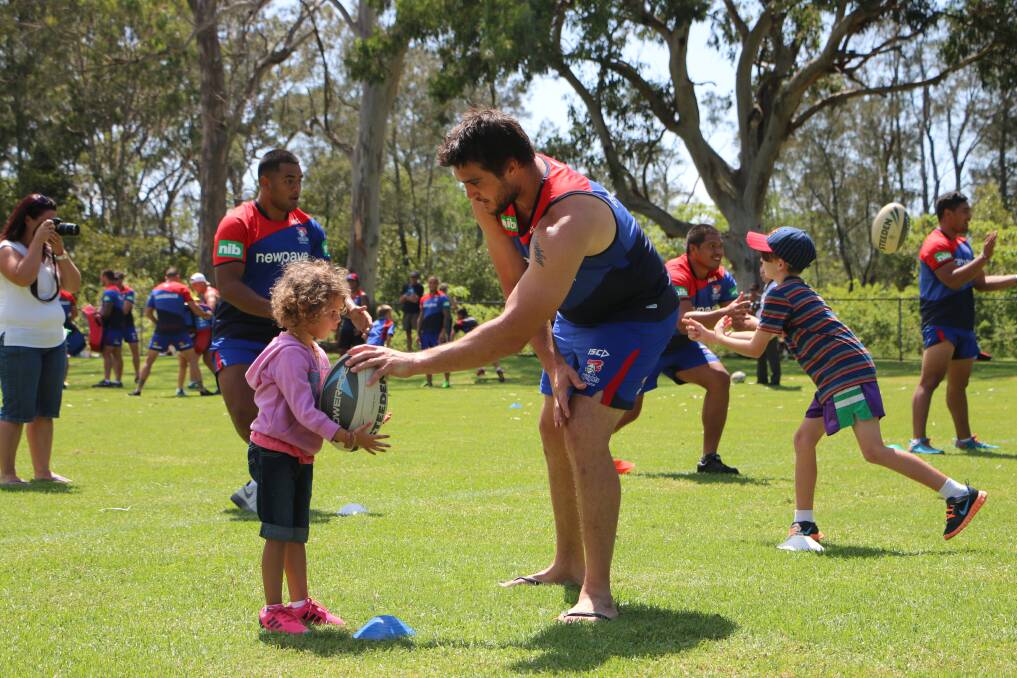 GENTLE GIANT: Knights' player Kade Snowden helps out one of the younger children at the training session. Picture by Jamieson Murphy.