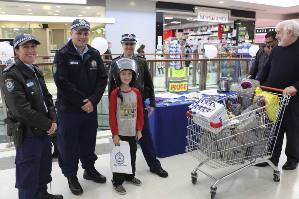 PROACTIVE: Zane Barnett tries on a police helmet with Senior Constable Holly Smith, Constable Alex Dascanio and Senior Constable Lee Upton at Morisset Square. Picture: Jamieson Murphy