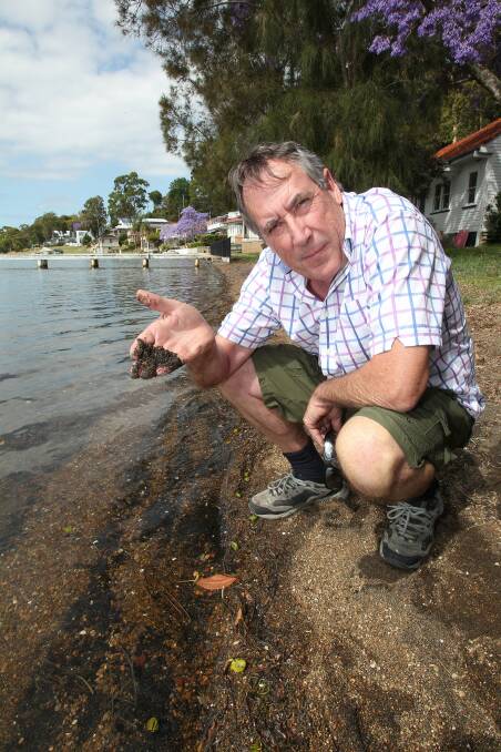 ALARMING: Jim Sullivan with black slag along the Lake Macquarie shore at Eleebana. Picture: Phil Hearne