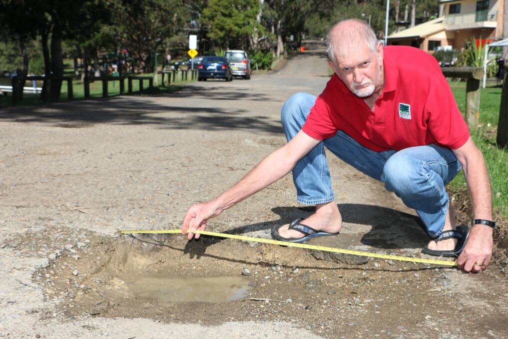 HOLE TRUTH: Ray Nelson measures one of the potholes on Watkins Road. Picture: Jamieson Murphy