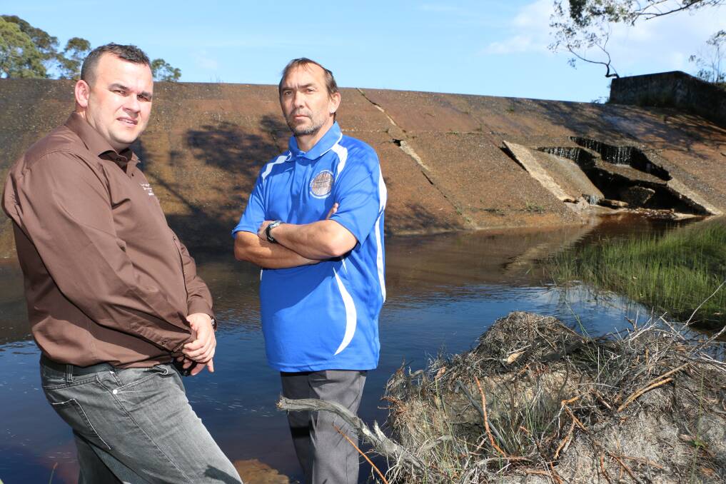 HOLE STORY: Biraban LALC’s Craig Foreshew, left, and Des Barton inspect the damaged weir at the Pourmalong Creek dam in Morisset this week.  Picture: Jamieson Murphy