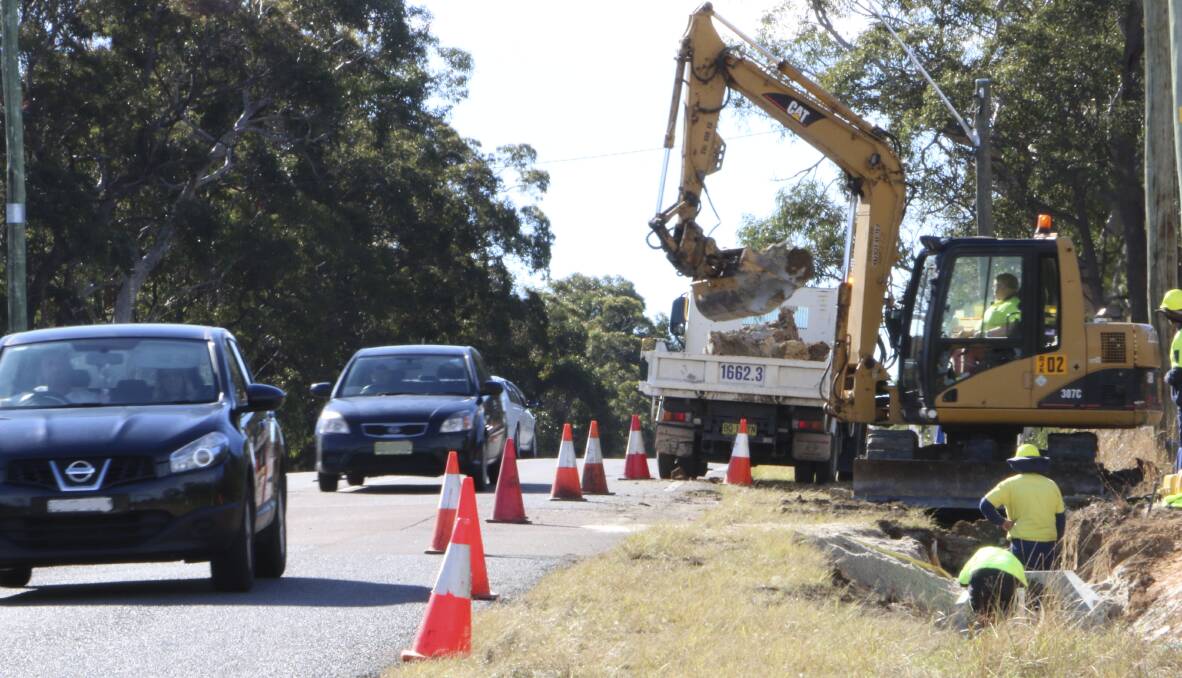 SLOW DOWN: Council staff at work on the Wyee intersection on Monday. Police are enforcing the 40km/h speed limit in the area. Picture: David Stewart