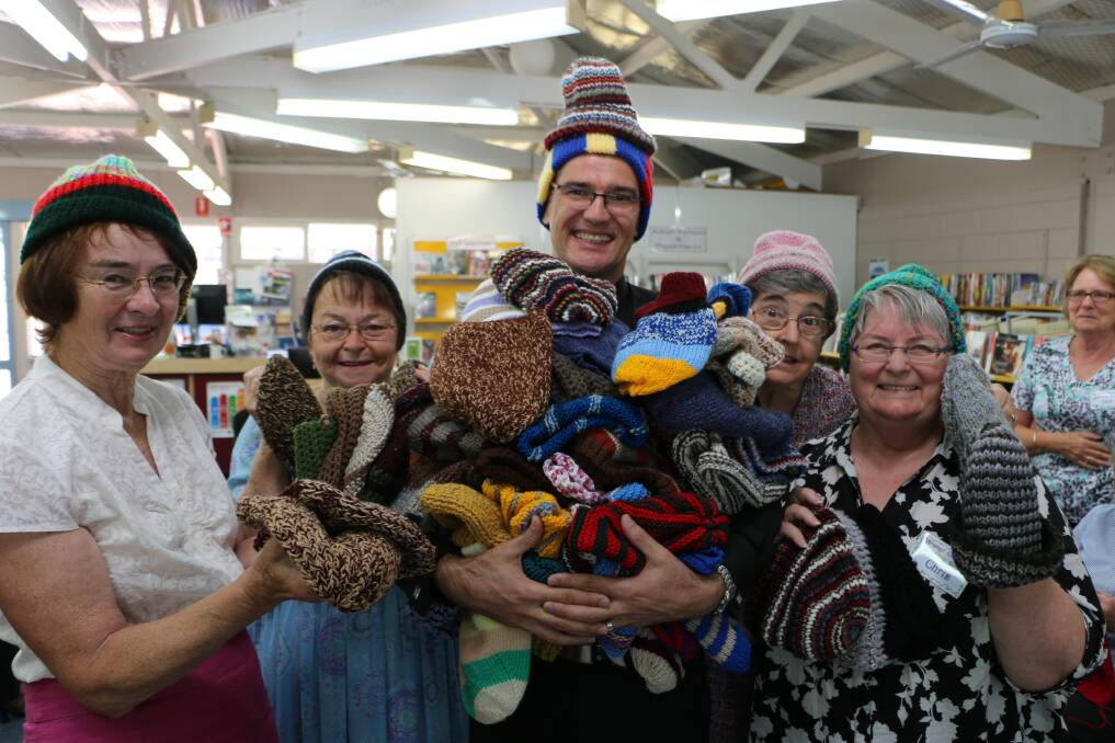 WITH LOVE: The Reverend Garry Dodd with, from left, the knitting group's Bernie Gill, Marg Tomlinson-Smith, Cath Bender and founder Chris Langshaw, at Wangi Library. Picture: David Stewart