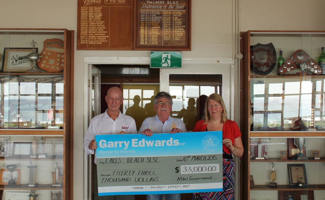 UPGRADE: Member for Swansea Garry Edwards, centre, presents the grant funding to Lakes Beach Surf Life Saving Club president Lou Carey and secretary Sharon Falzon.