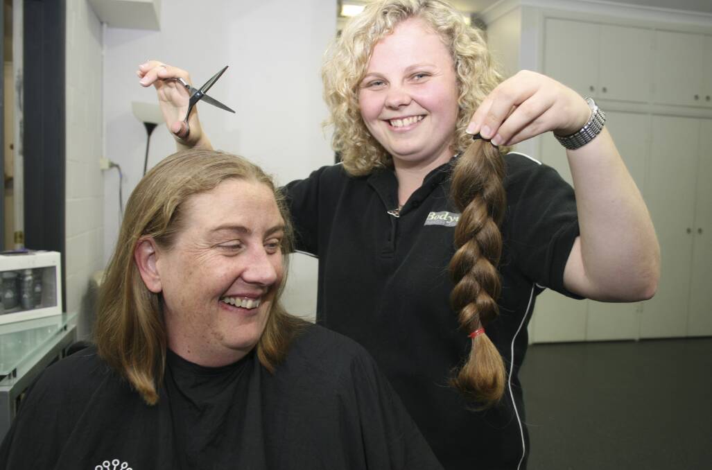 ENCORE: Kathy Mannile, of Southlakes Autoglass, has her ponytail lopped by friend Joanne Watts, of Bodywise Smash Repairs, in 2012. She's repeating the dose today at 1pm. Picture: David Stewart