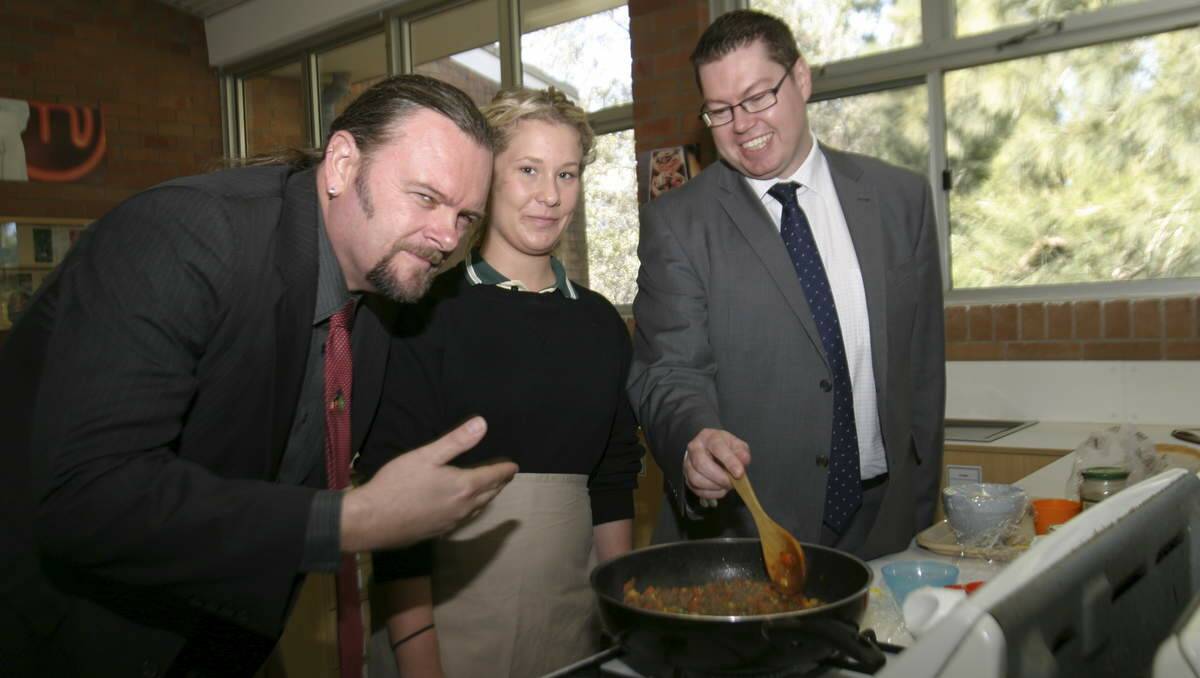 ON THE MENU: Principal Mark Snedden appreciates the dish being prepared by student Shannon King, with some help from Pat Conroy, in Morisset High School’s home economics rooms. Picture: David Stewart