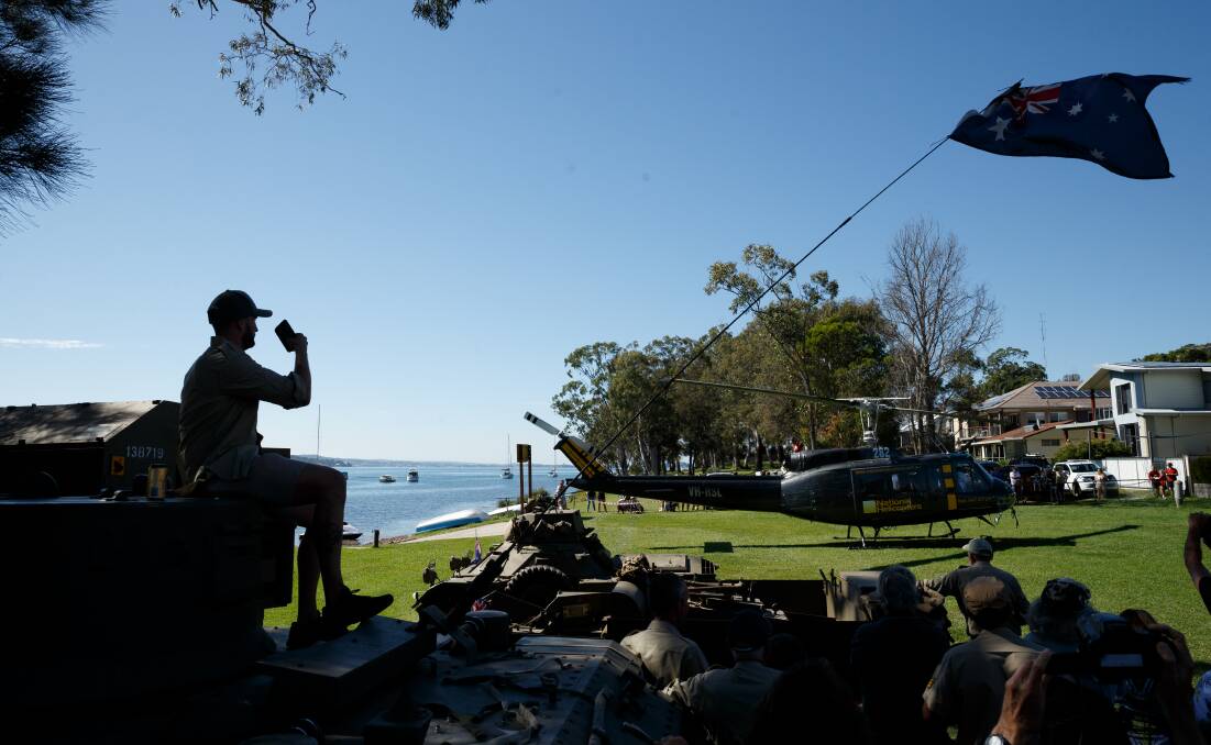 WE REMEMBER: A man sitting on a tank takes a photo from of a helicopter that landed on the foreshore at Wangi Wangi. 