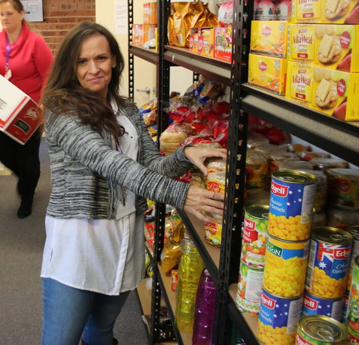 CHANGING LIVES: Christine Mastello stocking the shelves at the Southlake Marketplace in Cooranbong which offers free and low-cost food to the needy.