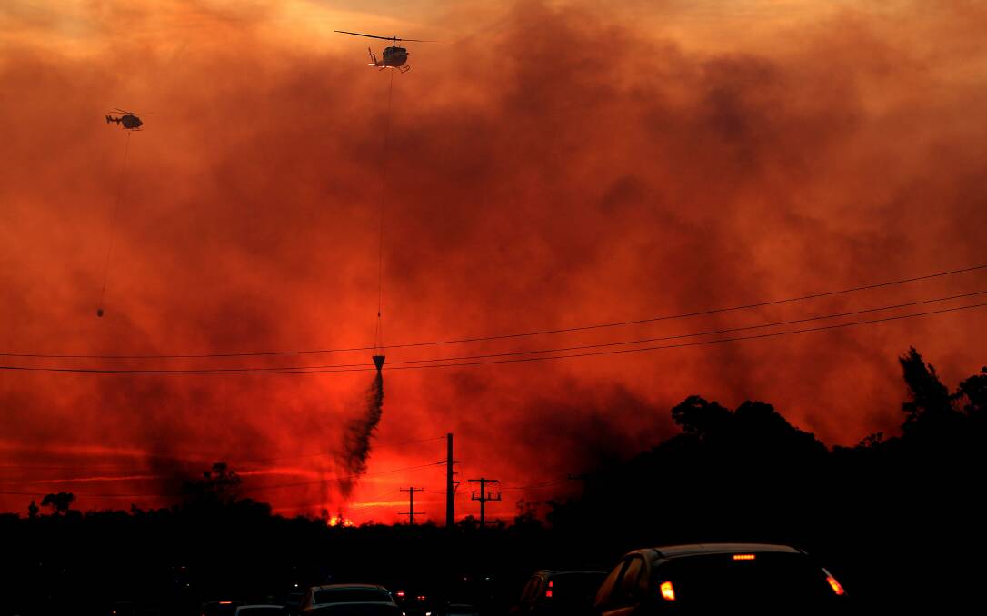 INTENSE: Helicopters water bomb the bushfire at Doyalson in 2013. Picture: Simone De Peak
