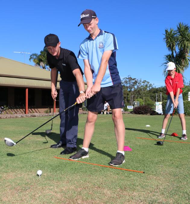 SWING PATH: Zach Churcher sets Liam Fitzpatrick's take-away on the right plane at the Morisset Golf Club junior clinic on Wednesday. Picture: David Stewart