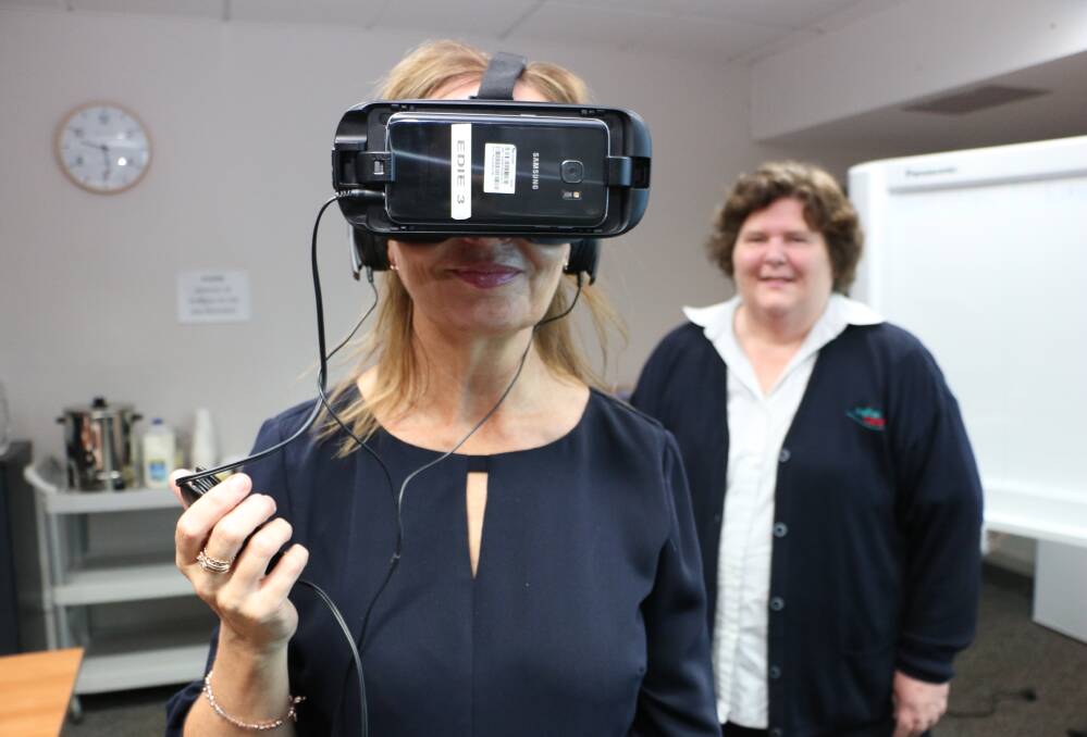 VIRTUAL WORLD: Anglican Care's Kylie Jacques dons an Educational Dementia Immersive Experience (EDIE) headset as Janet Sykes looks on at the workshop in Booragul on Thursday. Picture: David Stewart