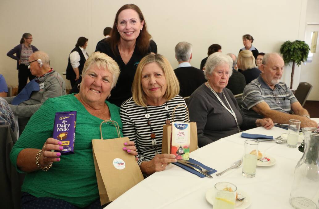 WELL DESERVED: Anglican Care's Kylie Jacques, standing, with carers Lorraine Garrard, left, and Patricia Rudd, who had fun exploring the contents of their gift bags at the lunch at Toronto Diggers. Picture: David Stewart