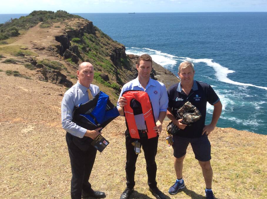 ROCK SAFETY: Cr Greg Best, left, with Chris Parker the CEO of Central Coast Surf Life Saving, and Cr Adam Troy, with a selection of modern life jackets that could be saving rock fishers at Wybung Head. Picture: Supplied.