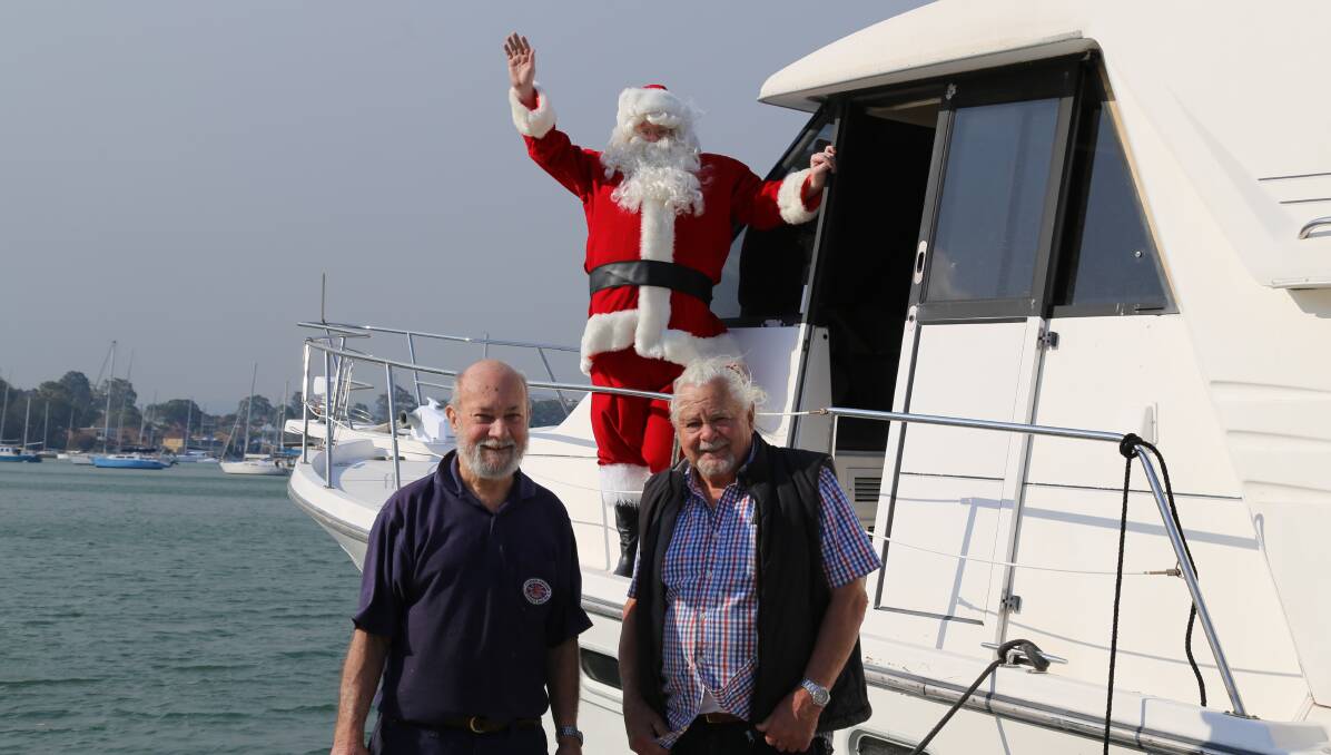 JOLLY: Rotarian Vic Lewis with boat owner Trevor Mears and Santa at Toronto. Santa will be visiting spots around Lake Macquarie on Christmas Eve.