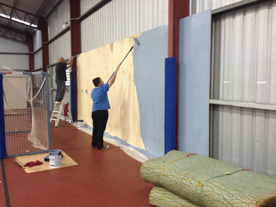 WALL TO WALL: Southlake Men's Shed members painting the wood panelling they installed at Morisset PCYC.