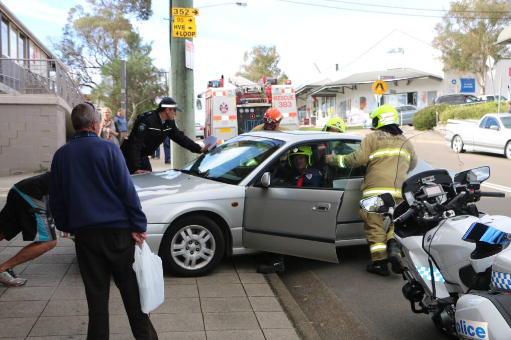 ROLLED BACK: Fire and Rescue NSW personnel from Morisset help to roll the car back onto Yambo Street.