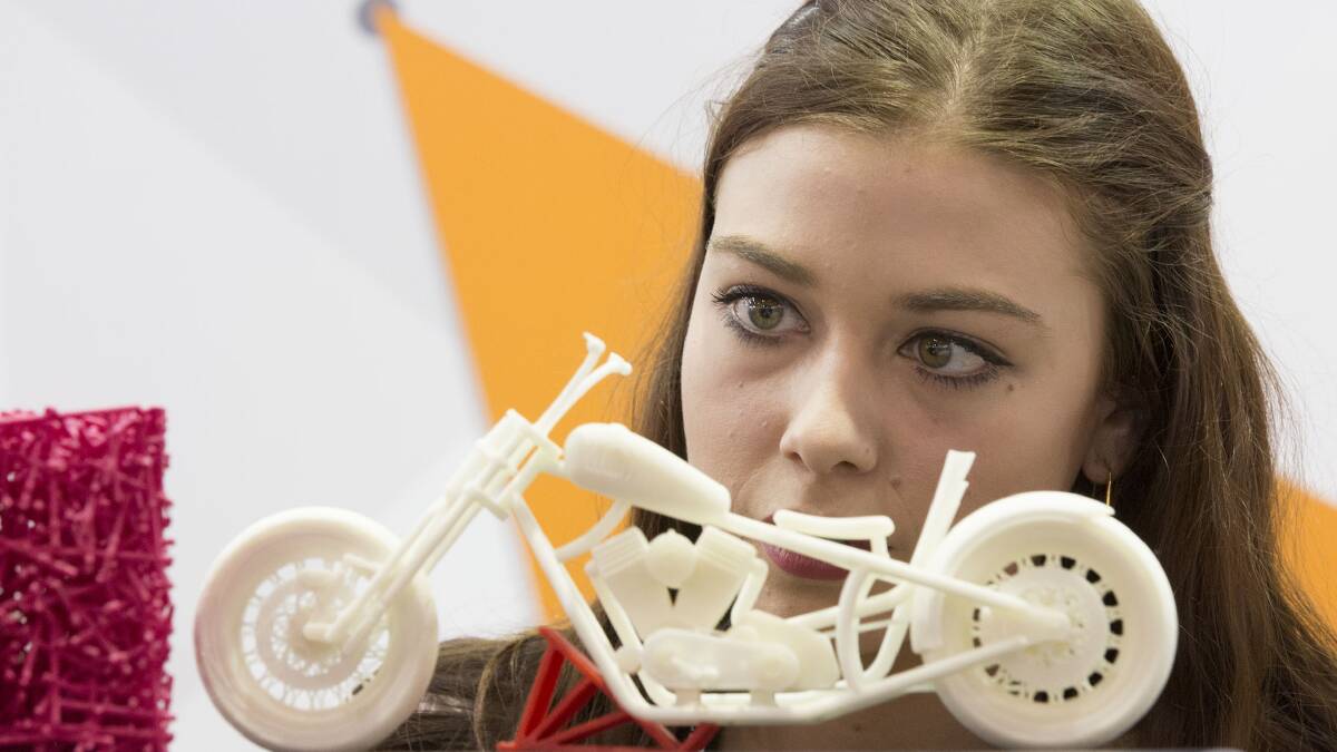 TECHNOLOGY: A woman inspects a model motorcycle generated by a 3D printer. Picture: Jessica Hromas