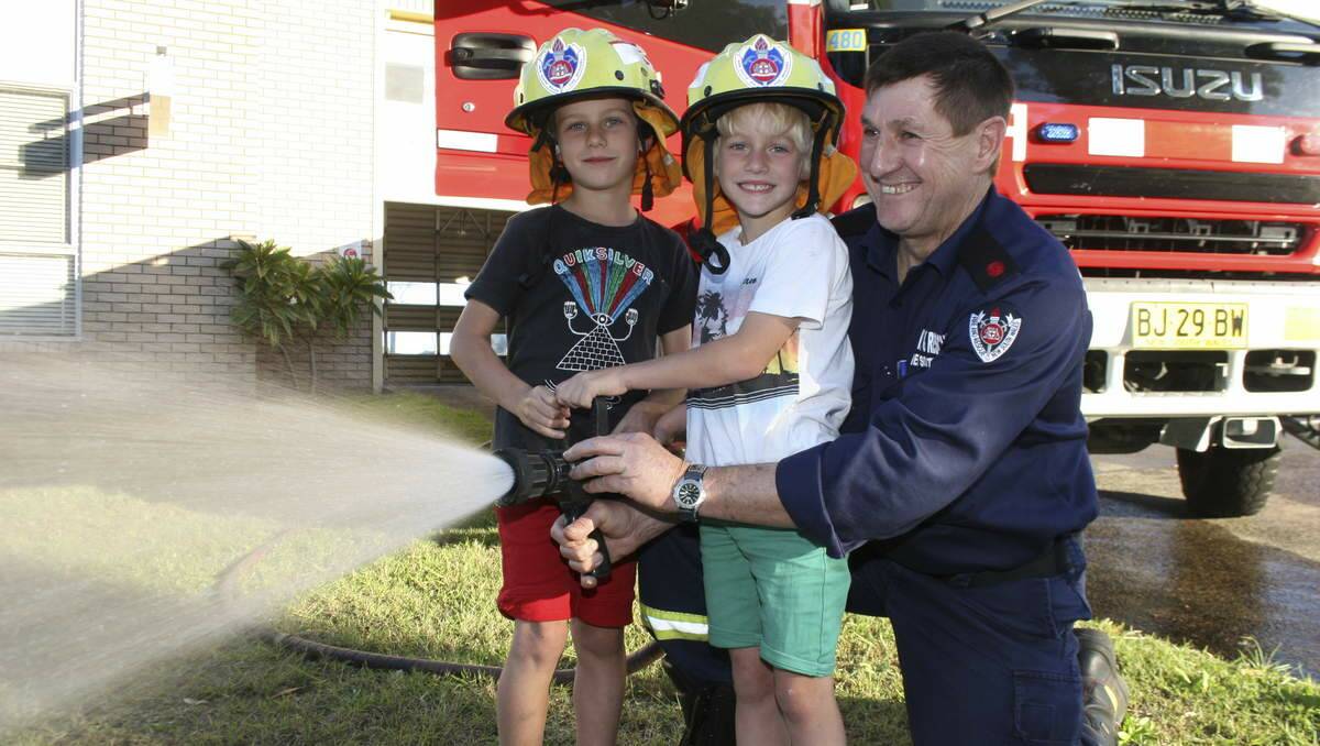 MAKING A SPLASH: James and Lucas Reddish test this Morisset fire truck's hose under the watchful eye of their grandfather Jim Reddish. Picture: David Stewart