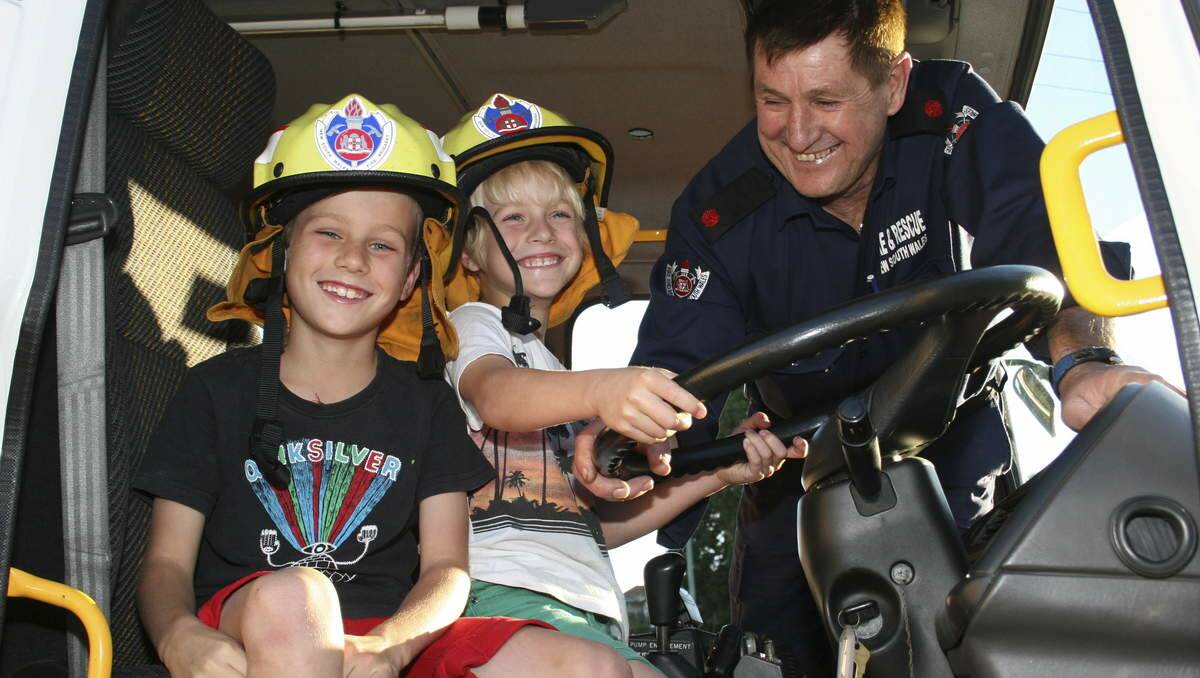 DRIVER'S SEAT: Deputy captain at Fire and Rescue NSW's Morisset station, Jim Reddish, gives his grandsons James (left) and Lucas Reddish a sneak preview of some open day fun aboard a fire truck. Picture: David Stewart